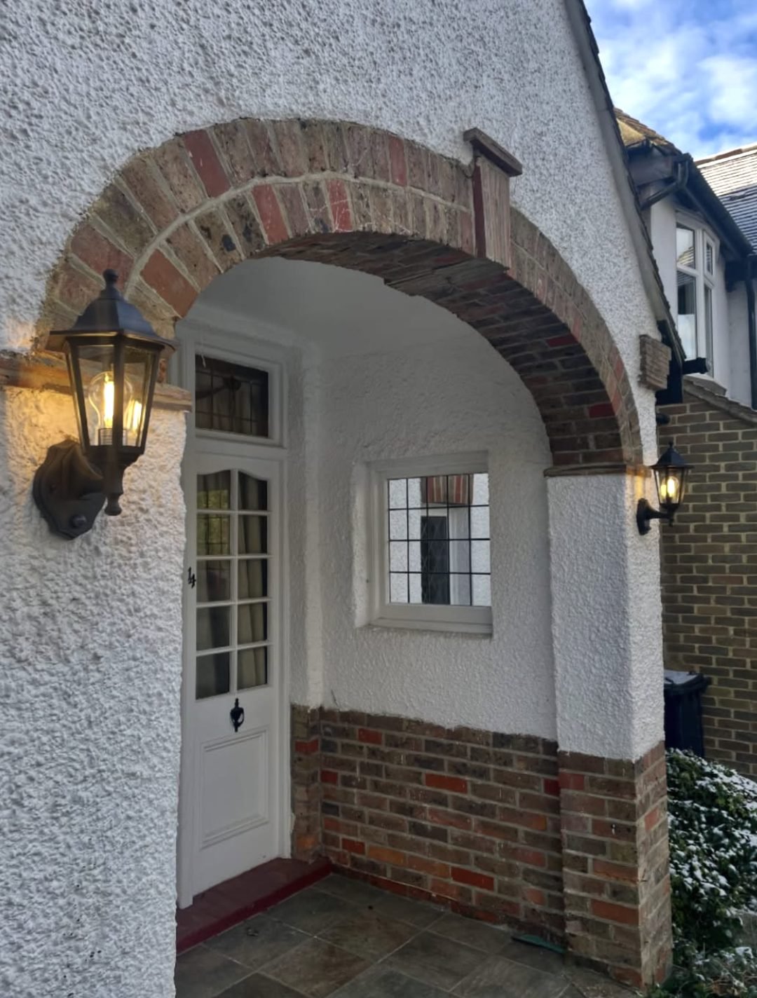 Two coach lanterns lit either side of an arched porch
